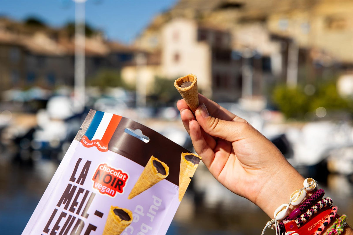 Mini cône au chocolat noir devant son sachet, sur le port