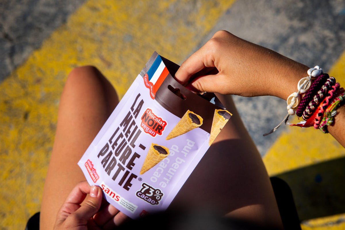 Sachet de mini cônes au chocolat noir 73 % ouvert entre les mains